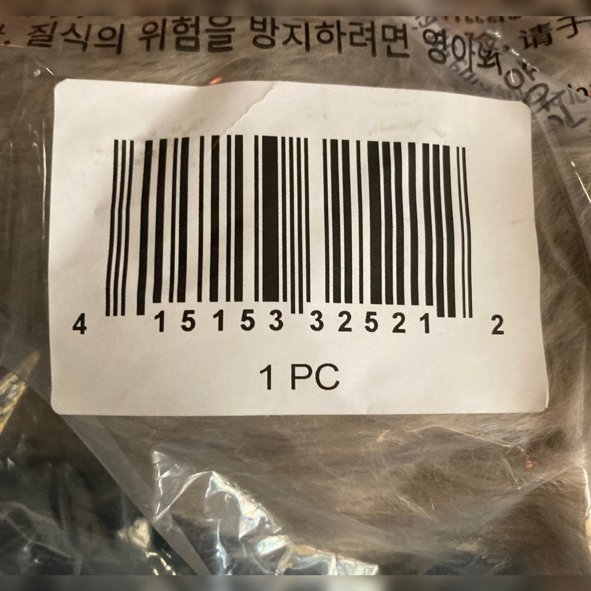 A close-up of a white barcode label attached to Disney's Max the sheepdog plush's packaging, with the text '1 PC' printed below it. The label has a black barcode and numbers.