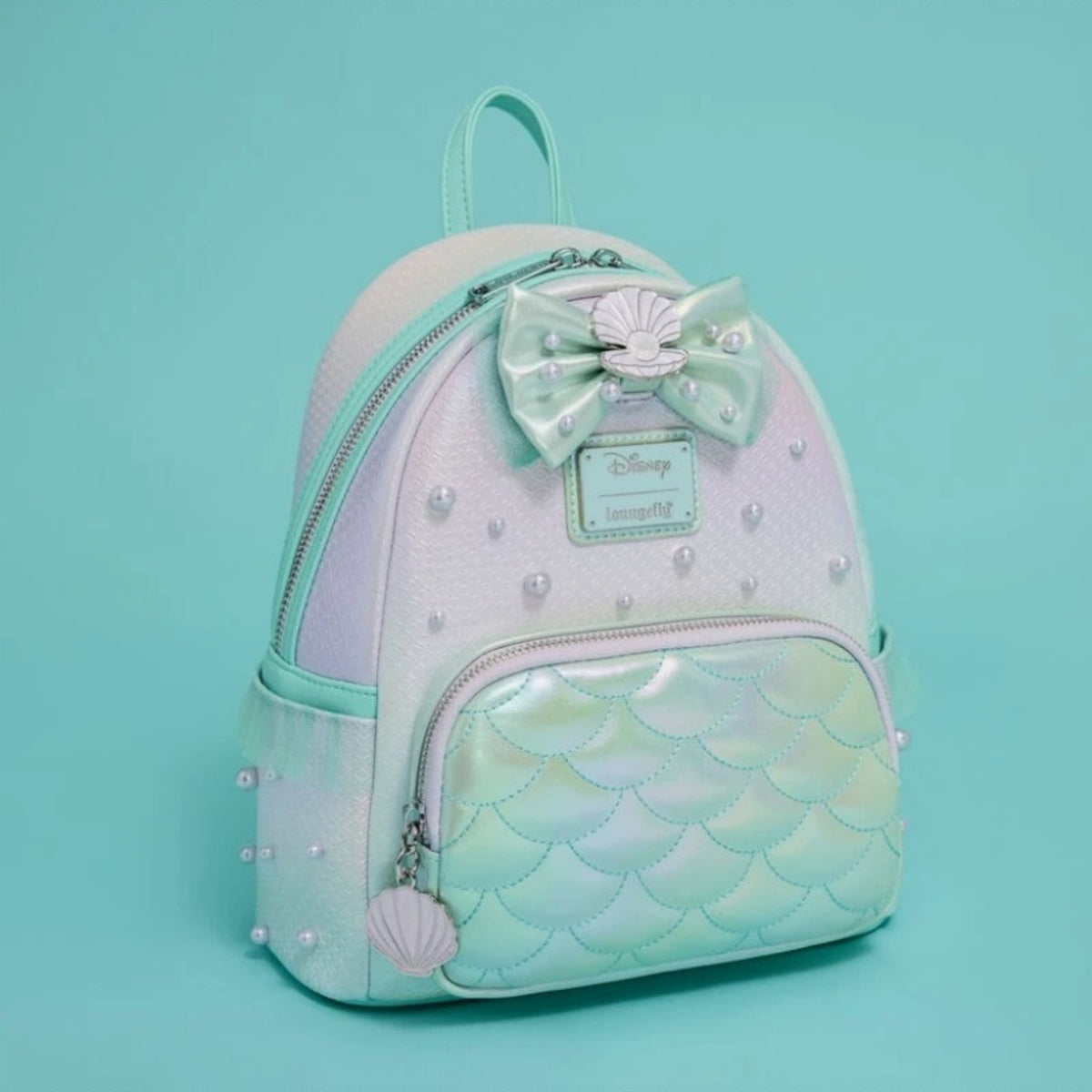 Loungefly Disney Princess Ariel Ombre Mermaid Scales & Pearls Backpack NWT at an angle on tourquoise backdrop