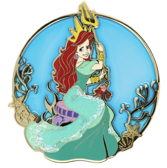 A circular Disney Princess pin featuring Ariel from The Little Mermaid, with red hair, a turquoise gown, a gold trident, and Sebastian on a light blue background with gold-toned decorative details.