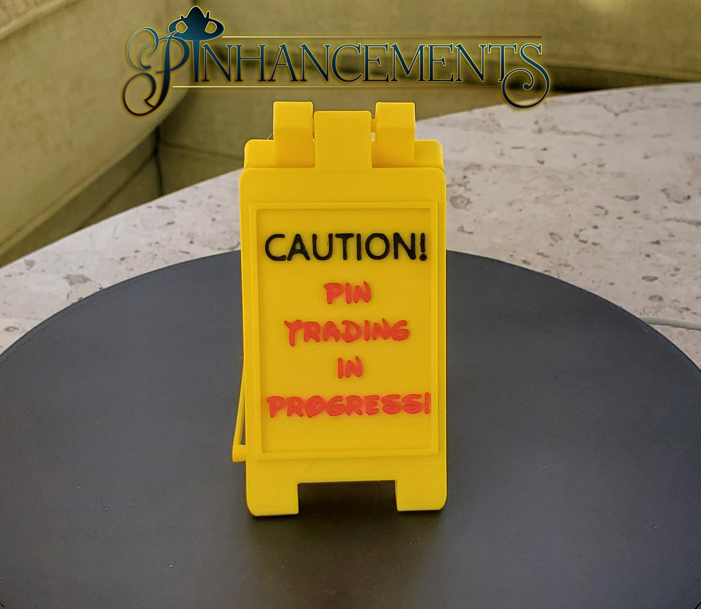 Yellow caution sign with Pin Trading text, branded 'Pin Enhancements'.