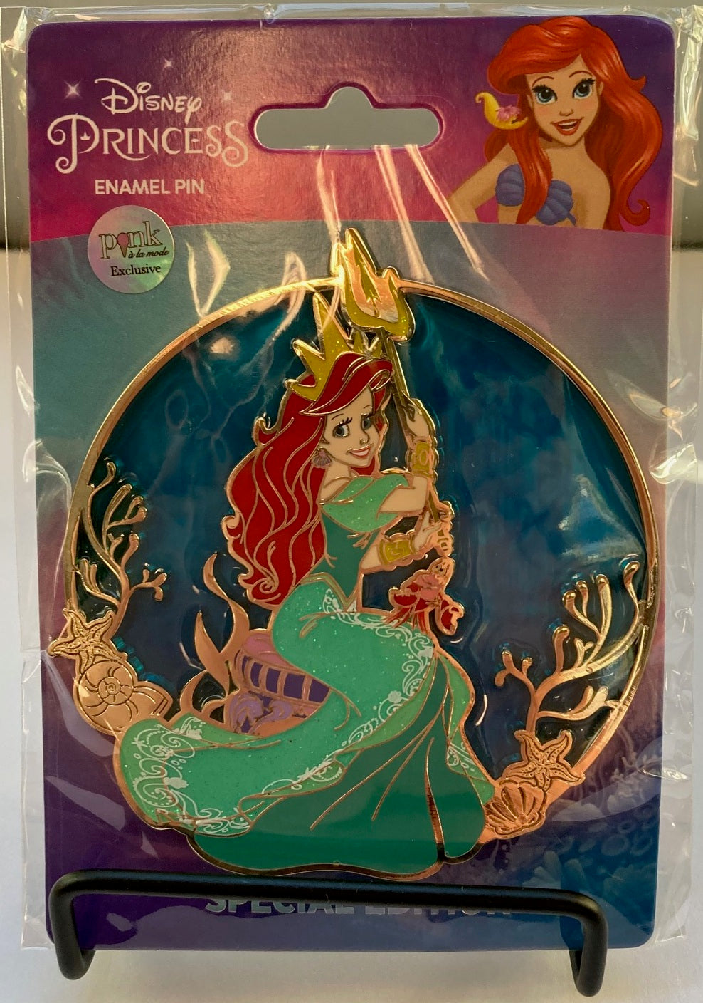 Disney Princess Ariel enamel pin in its original retail packaging on a stand.
