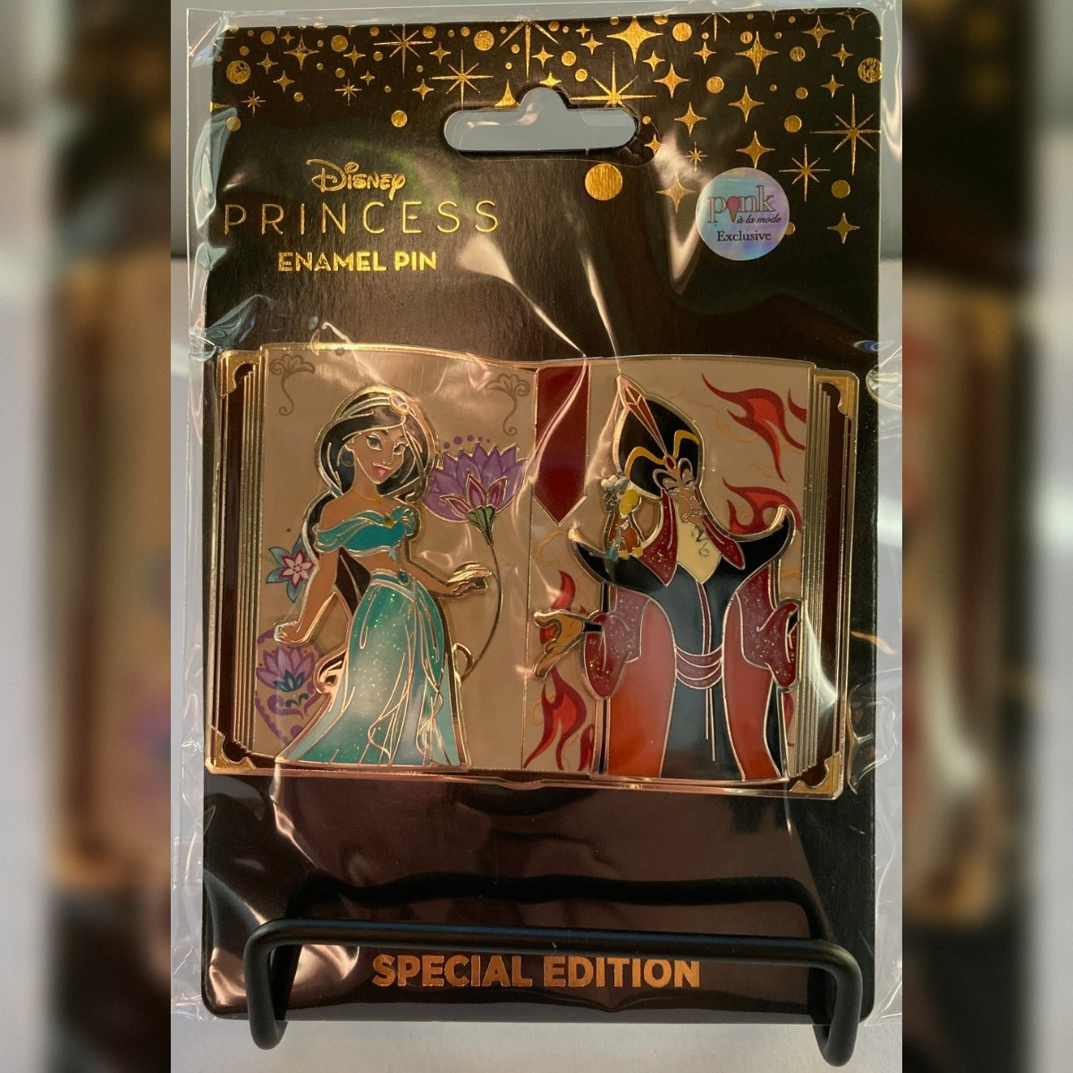 Front view of the Pink a la Mode LE 300 Jasmine and Jafar storybook enamel pin on a black metal display stand, sealed on its Special Edition Disney Princess card