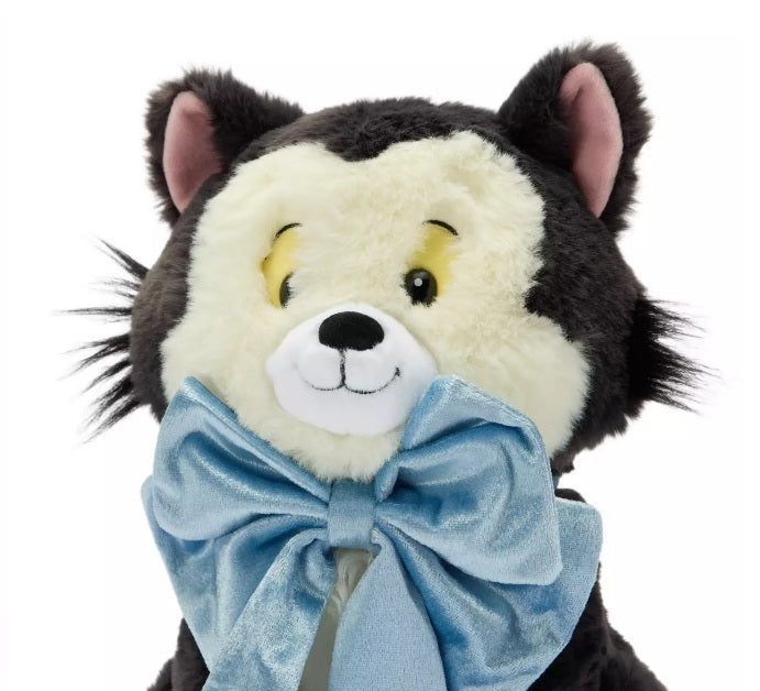 Disney Figaro plush with a cream and black fur pattern, yellow eyes, and a large light blue bow around its neck, shown against a plain white background.
