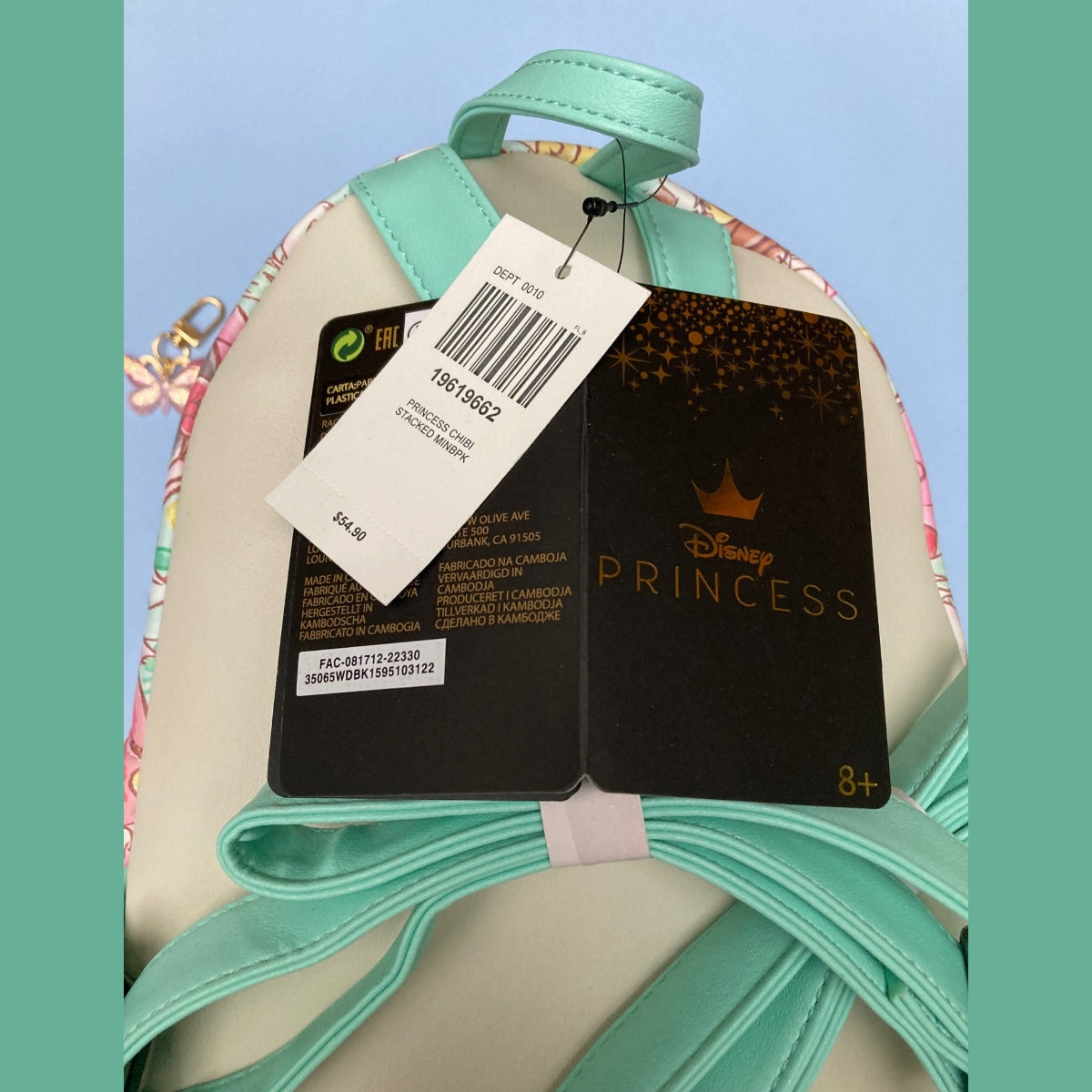 A Disney Princess Loungefly mini backpack with mint green straps and trim, a cream body, and an AOP patterned side panel. The bag is shown with its original tags attached, featuring a black tag with gold 'Disney Princess' lettering and a white barcode tag.