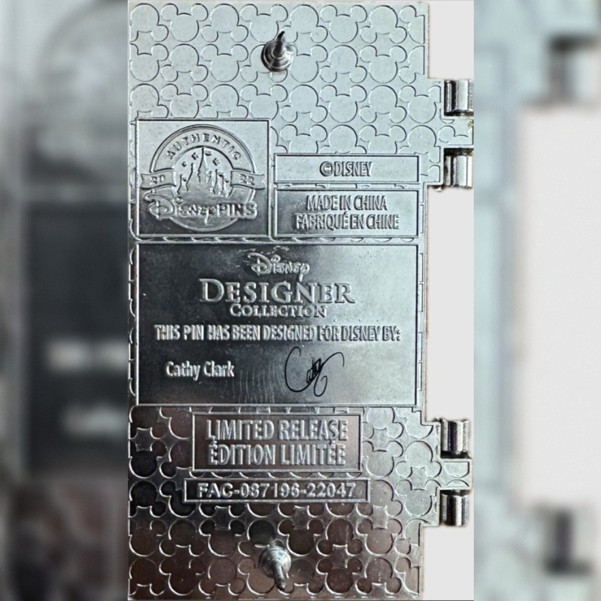 Close-up of the back of a silver metal Disney Designer Collection (Tiana) pin, showing engraved text including 'Disney Designer Collection,' 'Cathy Clark,' and 'Limited Release' and an FAC #.