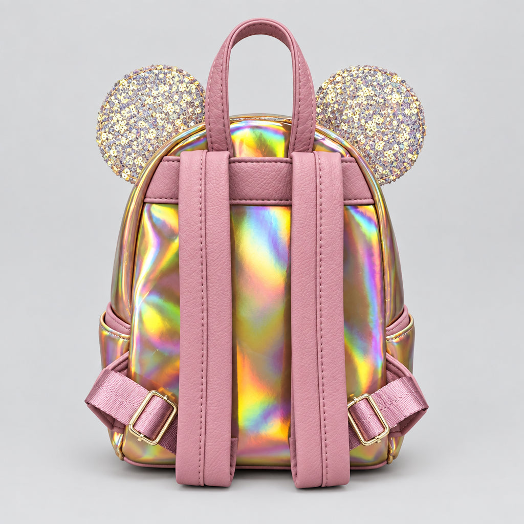 A Disney Parks Loungefly Minnie Mouse pink mini backpack with an iridescent holographic finish, featuring two round glittery mouse ears on top and pink straps, shown against a neutral gray background.