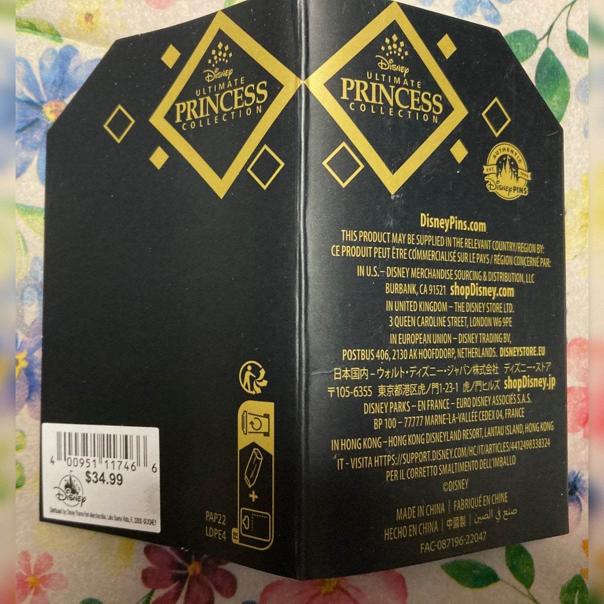 A black Disney Princess Collection product card shown open from the back, featuring gold logos, product information text, and a barcode on a floral background.
